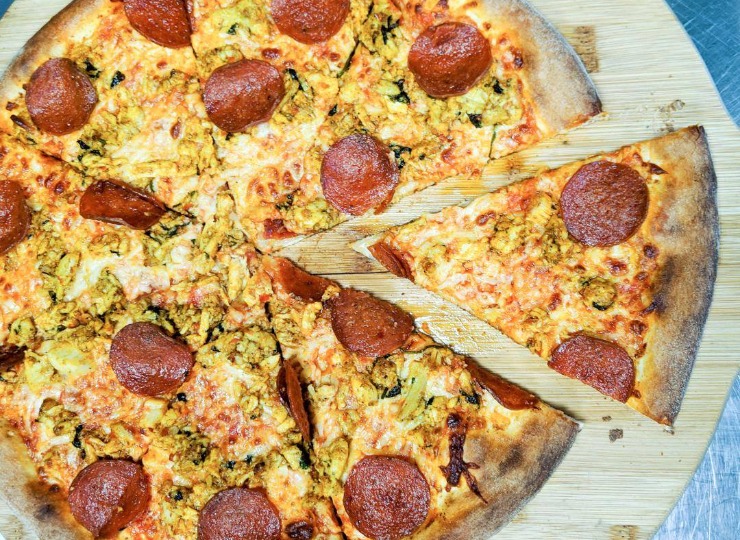 Pepperoni pizza sliced and sitting on a wooden board