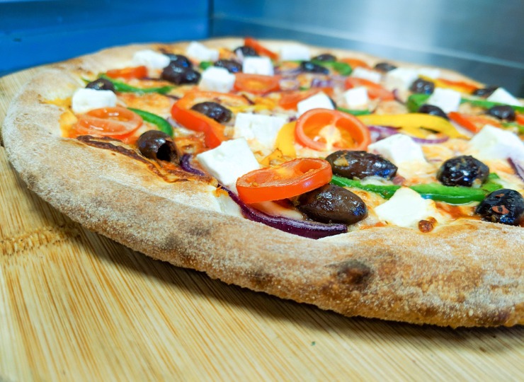 stone baked pizza topped with feta, olives and tomatoes