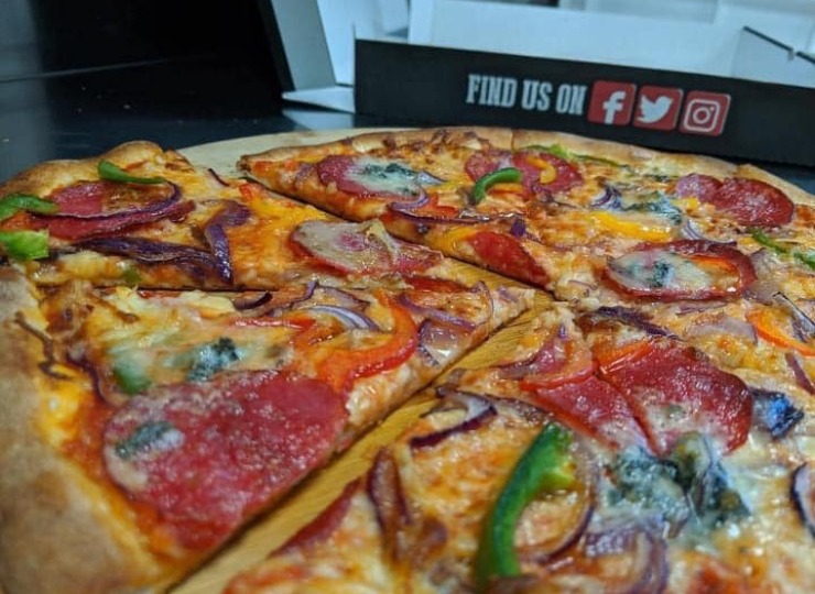 Pizza Luigi on a wooden board with a pizza box in the background