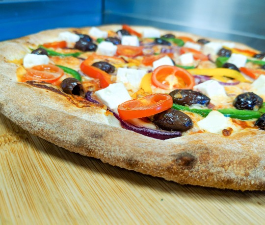stonebaked pizza topped with olives, peppers, feta and tomatoes